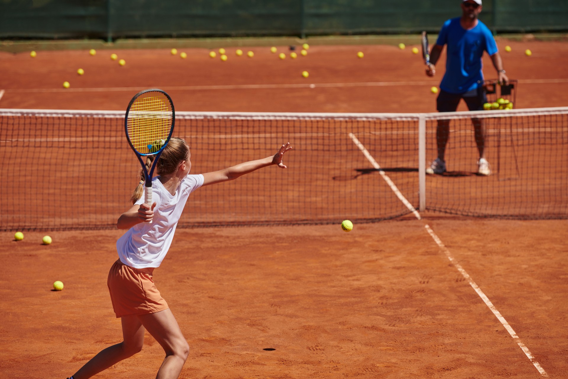 A professional tennis player and her coach training on a sunny day at the tennis court. Training and preparation of a professional tennis player
