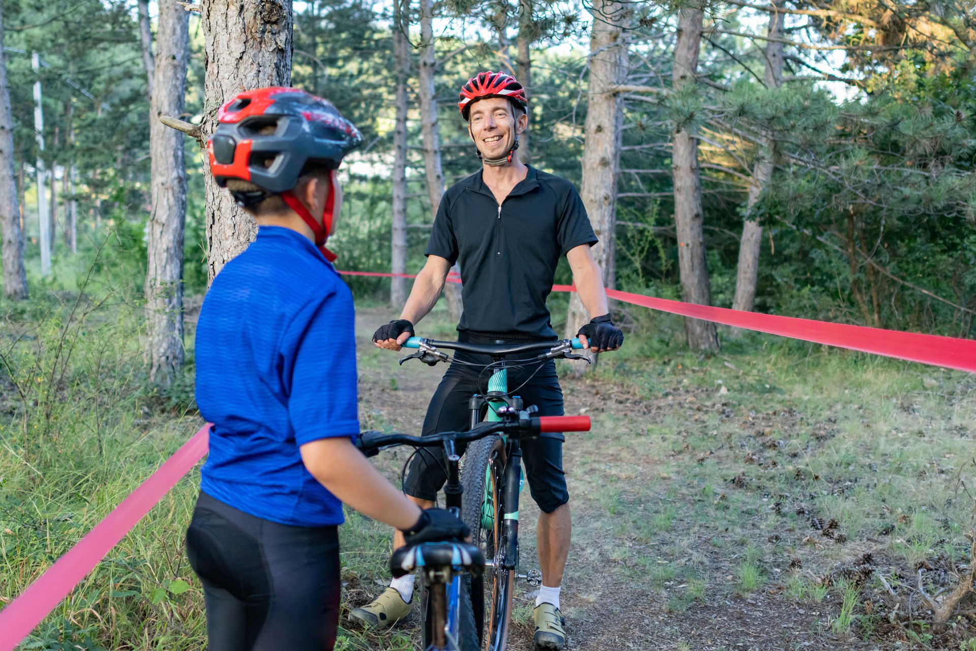 Father and son are competing in a mountain bike race. They are riding their bicycles on a marked trail or a race course during training.