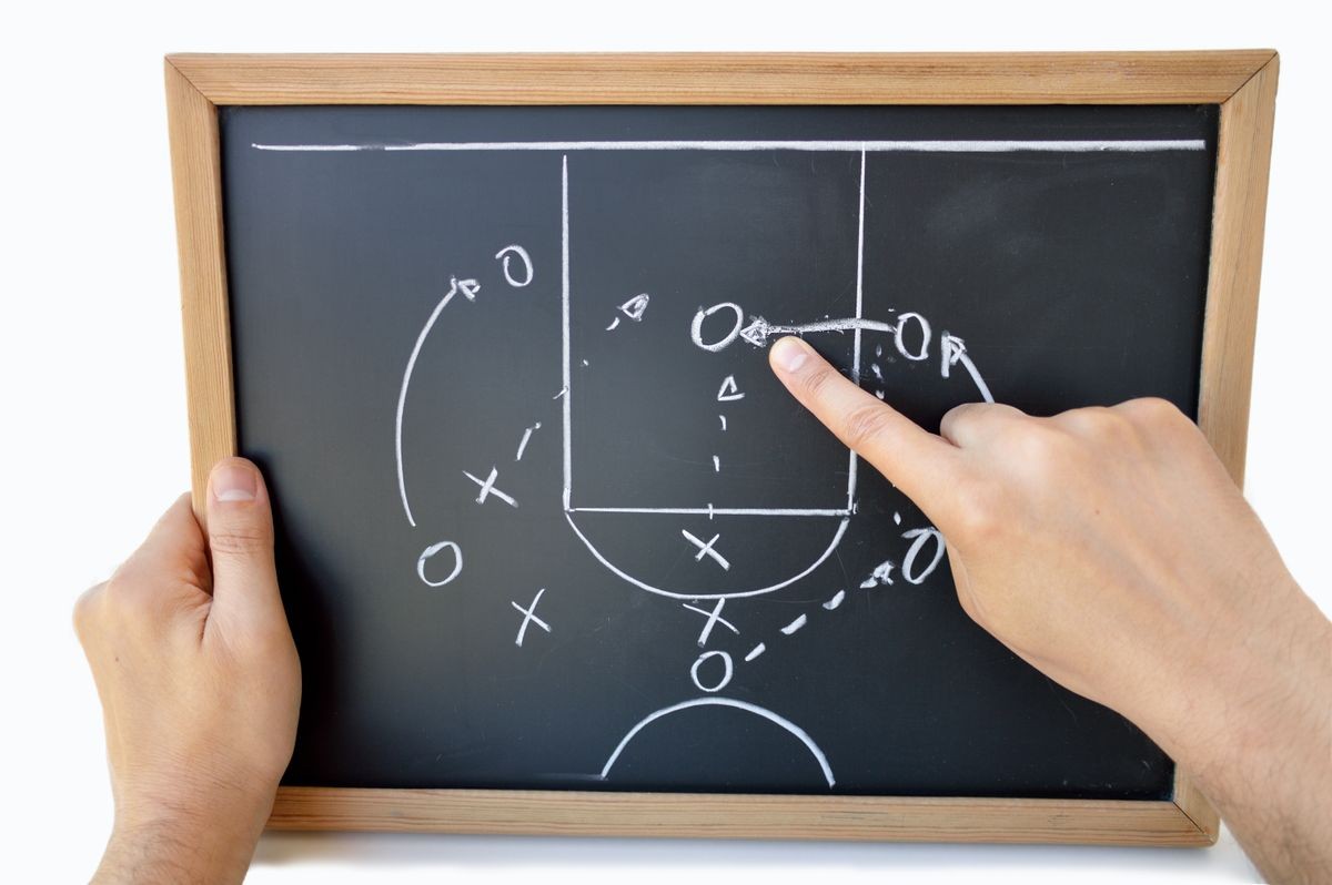 coach indicating with the finger the tactic of the meeting on the blackboard with white background